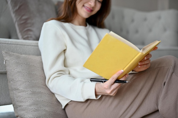 Asian female chilling in her living room reading a book or playing a word scramble game