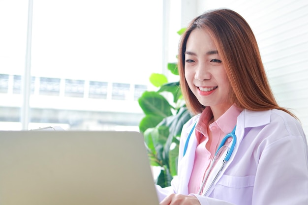 Asian female doctor sitting in office use a laptop computer Online video call talks to patients remotely online medical concept Hospital medical services