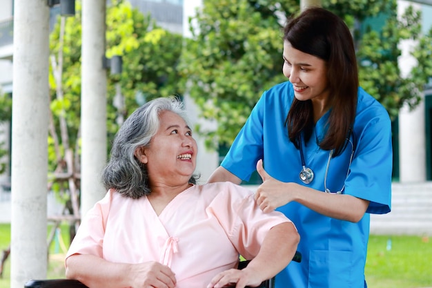 Asian female doctor treats an elderly patient sitting in a wheelchair Concept of medical services in hospitals surgical treatment of patients