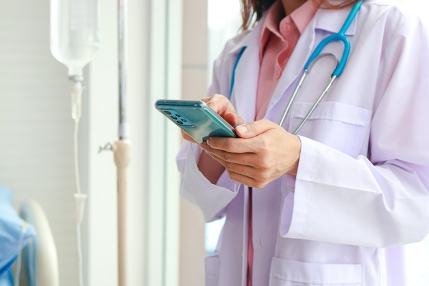 Asian female doctor working in office Holding a smartphone for online video calling talk to patients remotely online medical concept Hospital medical services