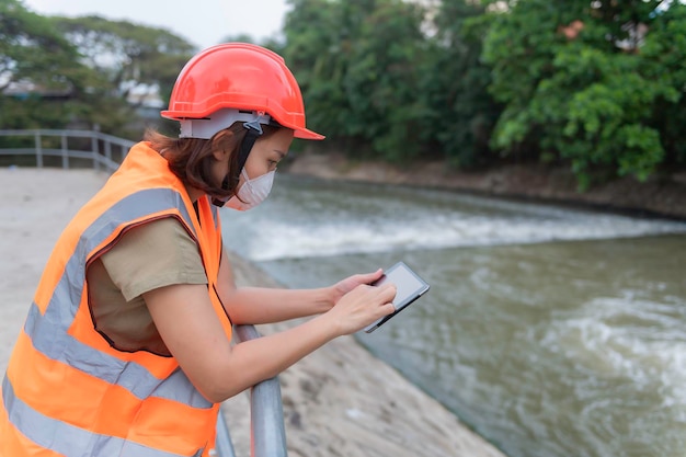 Asian Female engineering working xA at sewage treatment plantMarine biologist analysing water test resultsWorld environment day conceptCheck the PH value of the water before using it for treatment