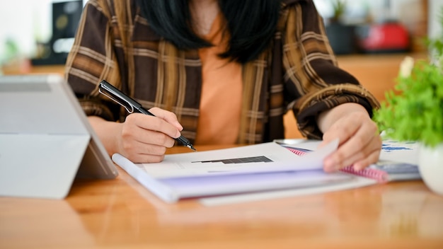 An Asian female in flannel shirt working on documents or paperwork cropped image