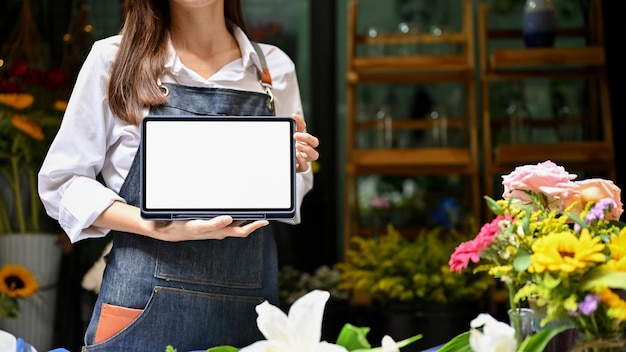 Asian female florist in apron showing or holding a tablet mockup cropped shot