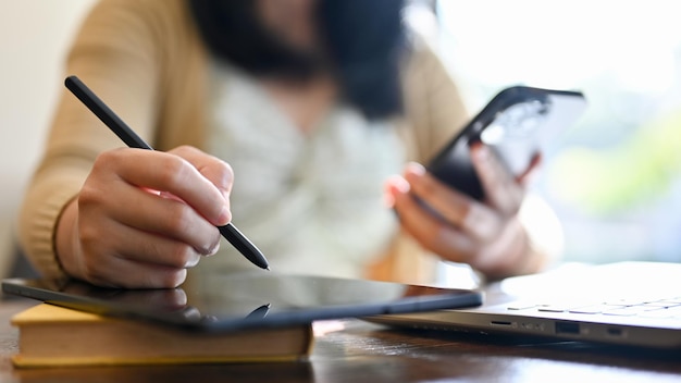 An Asian female freelancer using her digital tablet remote working at the coffee shop