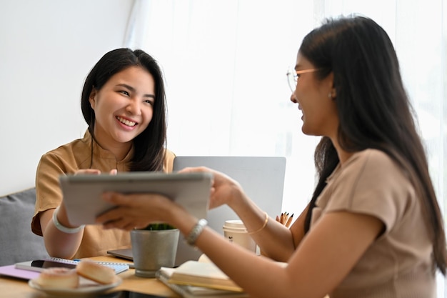 Asian female friends relaxing enjoy talking and looking at digital tablet together