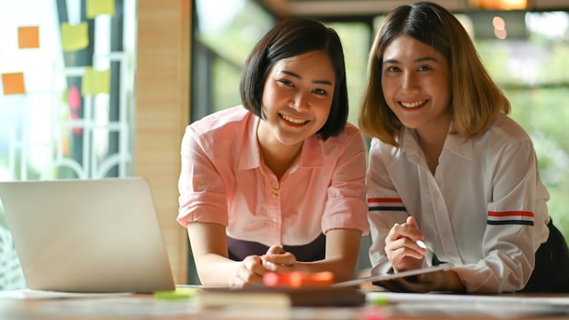 Asian female graphic designer working together at the office They use laptop and tablet.