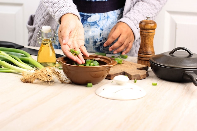 Asian Female Pour Green Spring Onion to the Bowl on Wooden Table, Cooking Step by Step in the Kitchen, Selected Focus with Copy Space