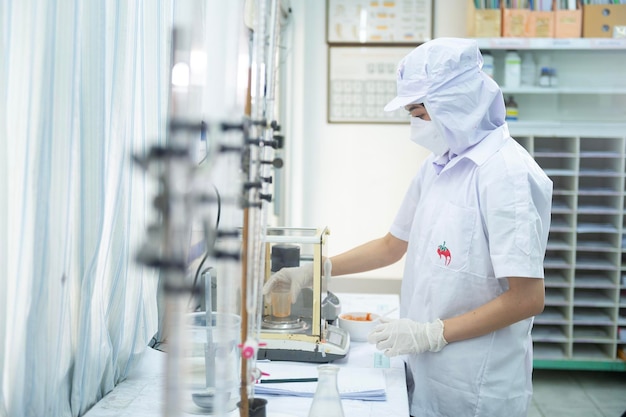 Asian female specialist in quality control lab examining tomato ingredient food in research lab food industry