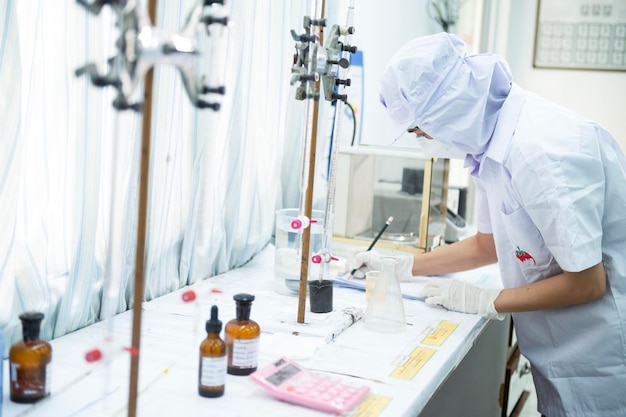 Asian female specialist in quality control lab examining tomato ingredient food in research lab food industry