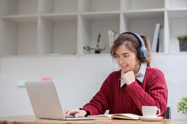 Asian female student study online in class study online wearing headphones watching video call zooming happy asian female learning language online with computer laptop