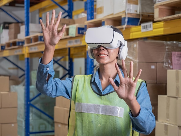 Asian Female warehouse supervisor using virtual reality headset doing inventory counting in the warehouse The concept of modern technologiesxA