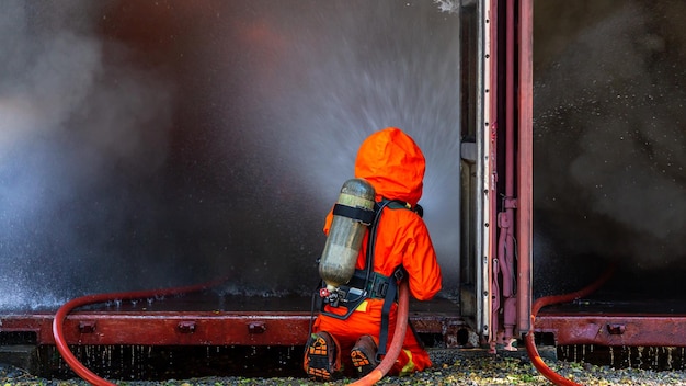 Asian firefighter on duty Asian fireman spraying high pressure water Fireman in fire fighting equipment uniform spray water from hose for fire fighting