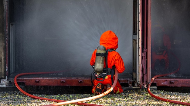 Asian firefighter on duty firefighting Asian fireman spraying high pressure water Fireman in fire fighting equipment uniform spray water from hose for fire fighting