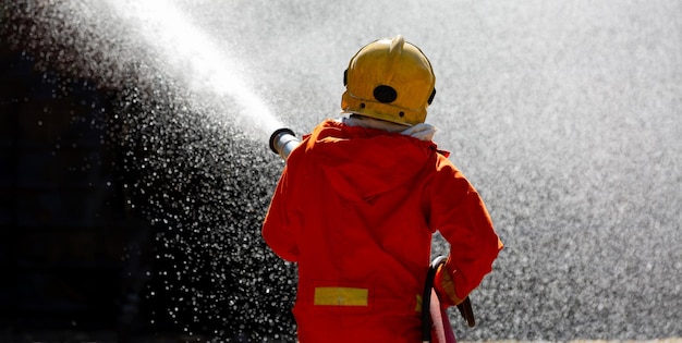 Asian firefighter on duty firefighting spraying chemical foam Asian fireman spraying high pressure chemical foam Fireman in fire fighting equipment uniform spray chemical from hose for fire fighting