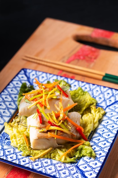 Asian food concept Chinese Steamed fish with ginger and soy sauce on black slate stone board with copy space