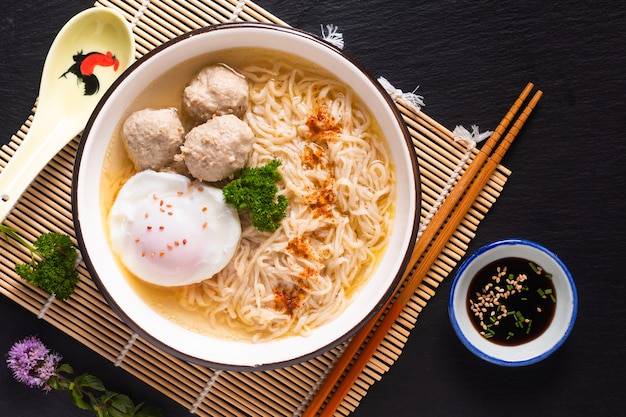 Asian food concept Egg noodles Ramen Asian style with meatball on bamboo matt black background with copy space