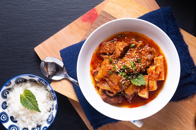 Asian food concept homemade Kimchi Beef Stew Kimchi Jjigae on wooden board and black slate stone with copy space