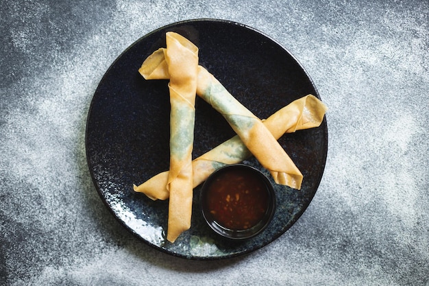 Asian food. Roll with vegetables and shrimp on a stylish plate. Dark background