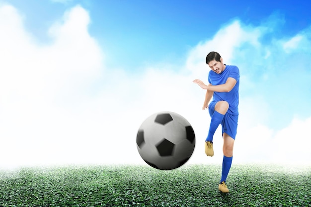 Asian football player man in a blue jersey kicking the ball