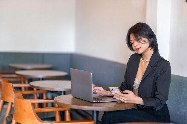 asian freelance people businesswoman read writing message on smartphone casual working with laptop computer in cafe coffee shop backgroundbusiness expressed confidence embolden and successful concept