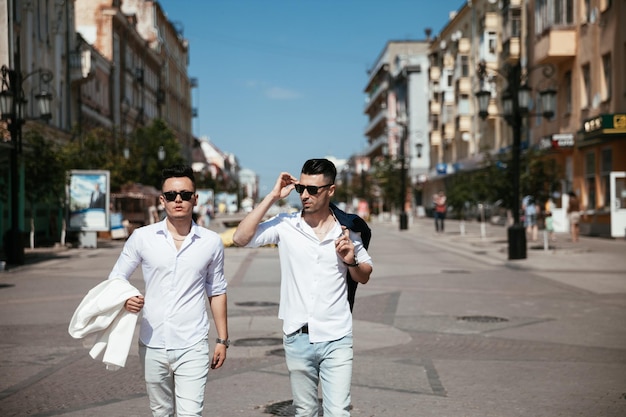 Asian gay couple is walking on the street looking at the sights having nice time together Well fashion dressed