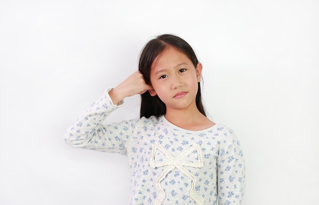 Asian girl child covers one ear with little finger not to hear and looks at camera isolated on white background