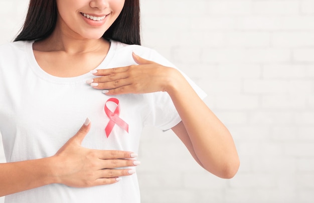 Asian Girl Framing Cancer Ribbon Symbol On TShirt Posing Indoors