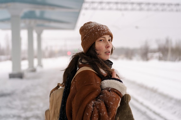 Photo asian girl going on winter journey feel cold waiting for train arrival outdoors at snowy station