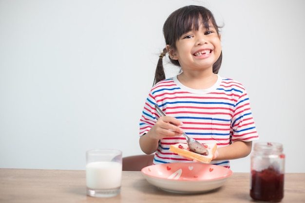 Asian girl having breakfast with bread and jam with a glass of milk