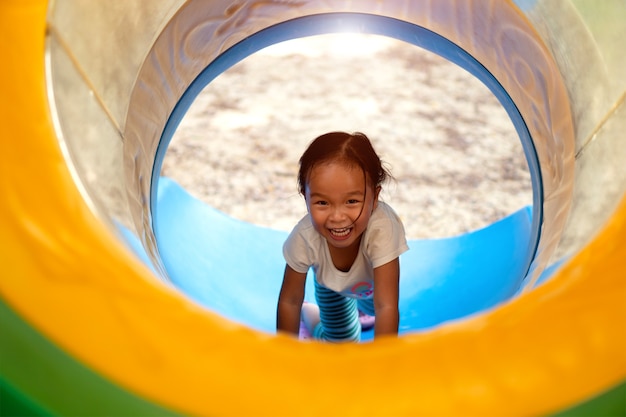 An Asian girl is enjoy on a playground equipment in a school.