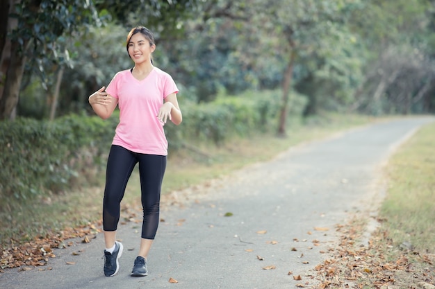 Asian girl is stretching her body warm muscles before going out for a run at the park