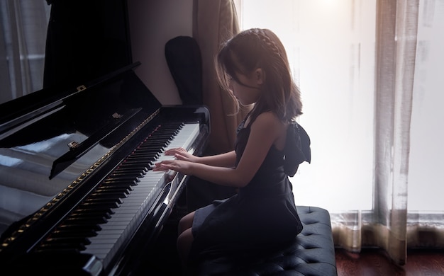 Asian girl kids practice play piano for practice to up skill of music ability