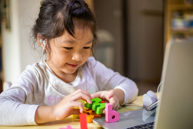 Asian girl learning alphabets online, Happy girl learn online with laptop at home.