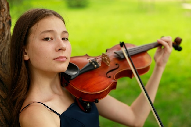 Asian girl in nature with violin. High quality photo