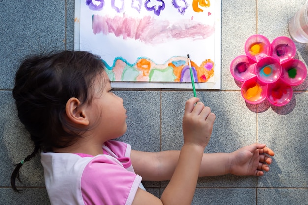 Asian girl painting with watercolor paints on paper