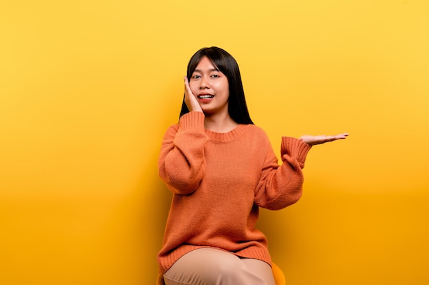 Asian girl Pretty wearing an orange casual dress yellow background Celebrate the victory with a happy smile and the winner's expression with a raised hand happy expression