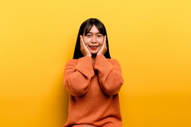 Asian girl Pretty wearing an orange casual dress yellow background Celebrate the victory with a happy smile and the winner's expression with a raised hand happy expression