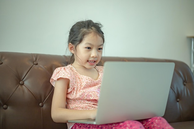 Asian girl sitting on couch with computer enjoy playing game