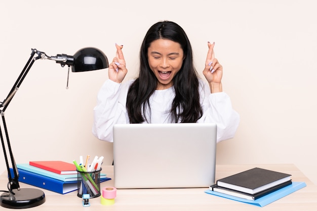 Asian girl sitting at a table with laptop and notebooks