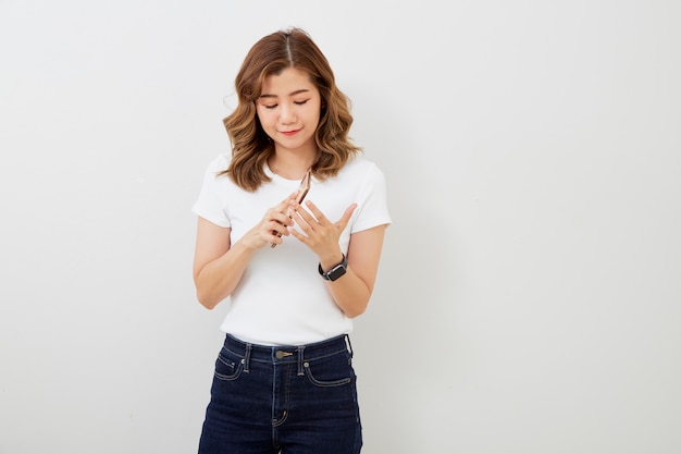 Asian girl using smartphone on grey wall