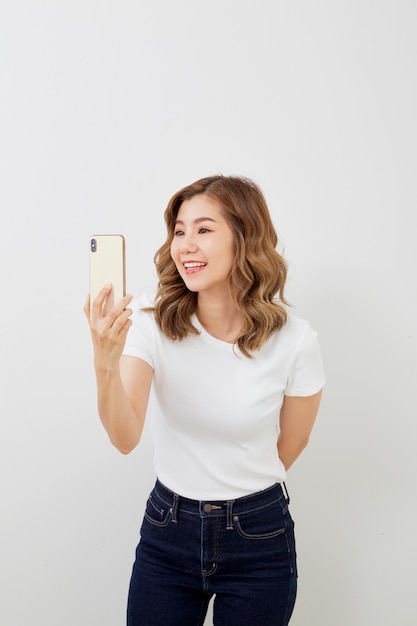 Asian girl using smartphone on grey wall