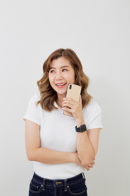 Asian girl using smartphone on grey wall