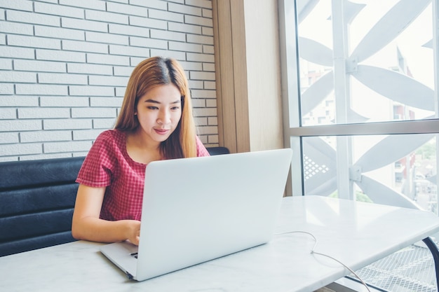 Asian girl working at a coffee shop with a laptop.female freelancer connecting to internet 