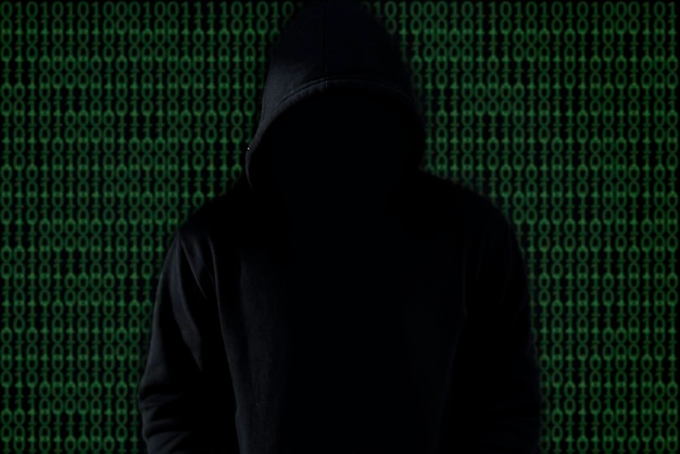 Asian hacker in black hood on black backgroundHack passwordhacking safety systems to steal information