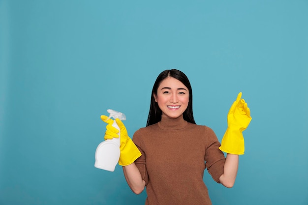 Asian happy glad housewife from daily work holding spray in yellow rubber glove, Cleaning home concept, Cheerful satisfied woman with positive mindset from day to day chores