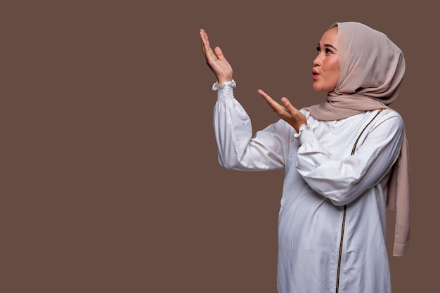 Asian hijab woman showing present gesture hand isolated on plain background.