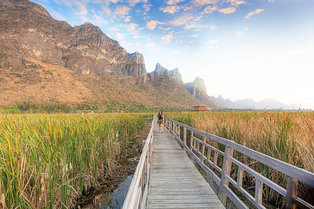 Asian hikers carry heavy backpacking on a small Pavilion outdoor hiking path on a wooden