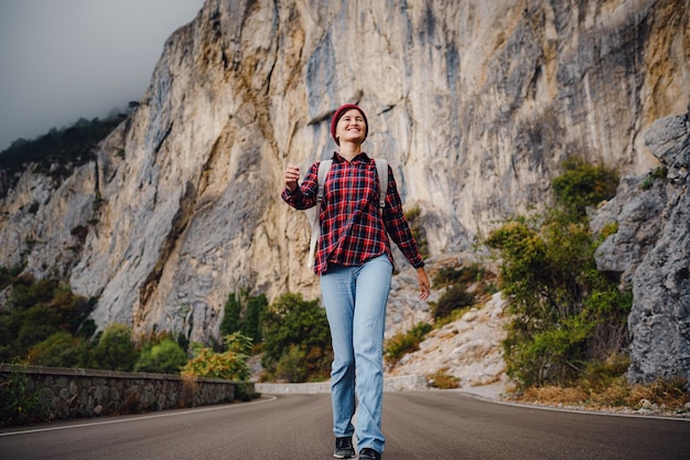 Asian hipster woman walking alone on a mountain highway on an autumn foggy day