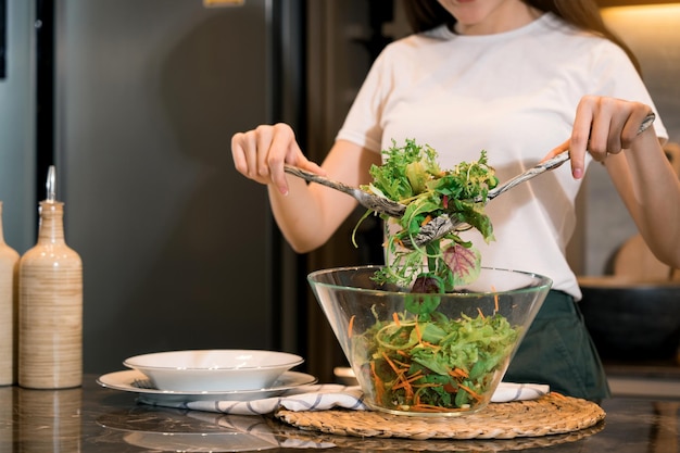 Asian housewife preparing fresh vegetables to make salad at home kitchen counter