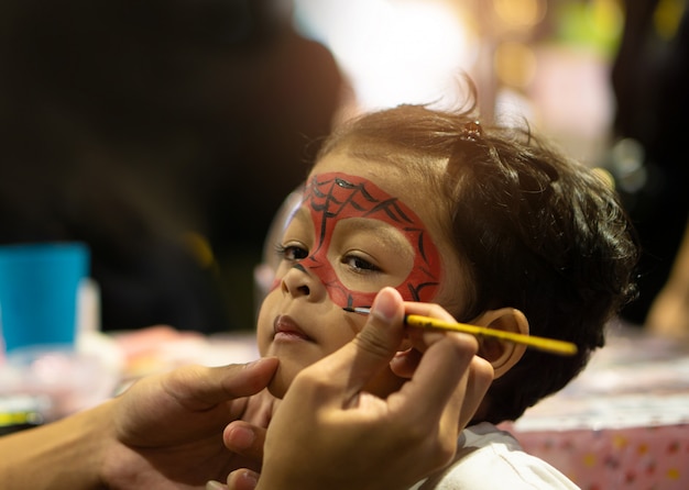 Asian kid boy with painted face as a spider